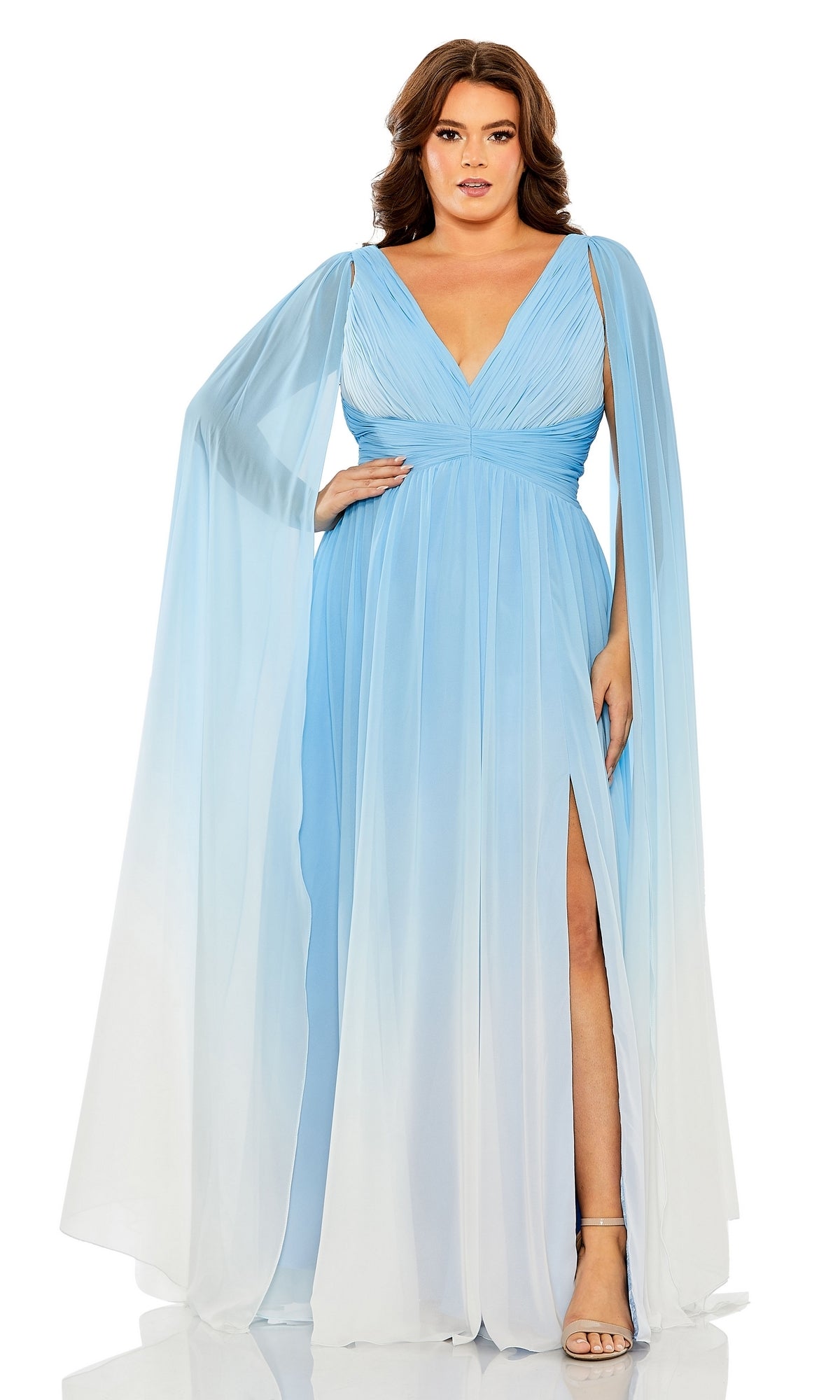 A woman in the Long Plus-Size Formal Dress 77010 by Mac Duggal, featuring pastel ombre fabric, draped cape sleeves, a deep V-neck, and a thigh-high slit, stands confidently with one hand on her hip.